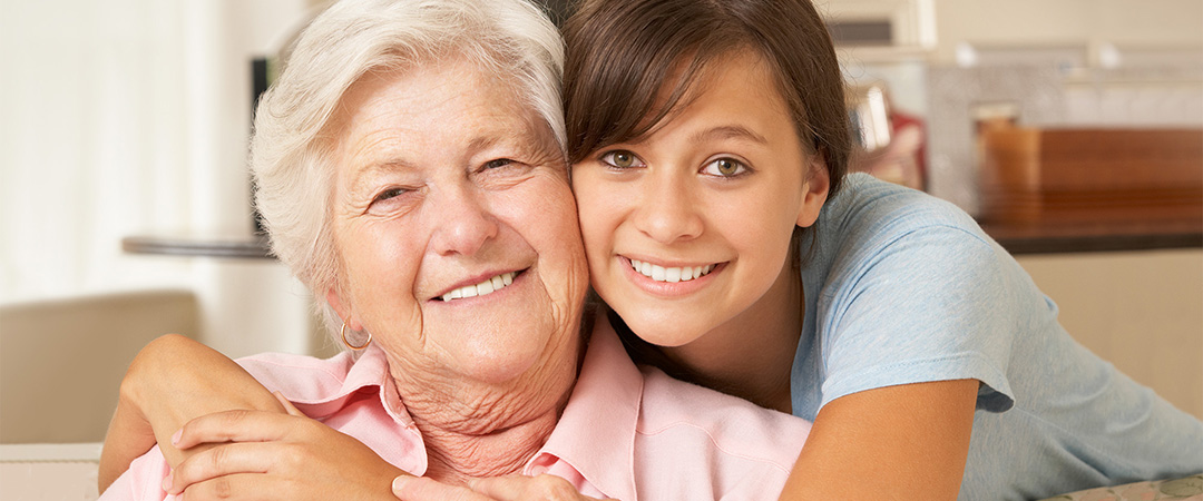 Young woman leaning down to hug her elderly relative
